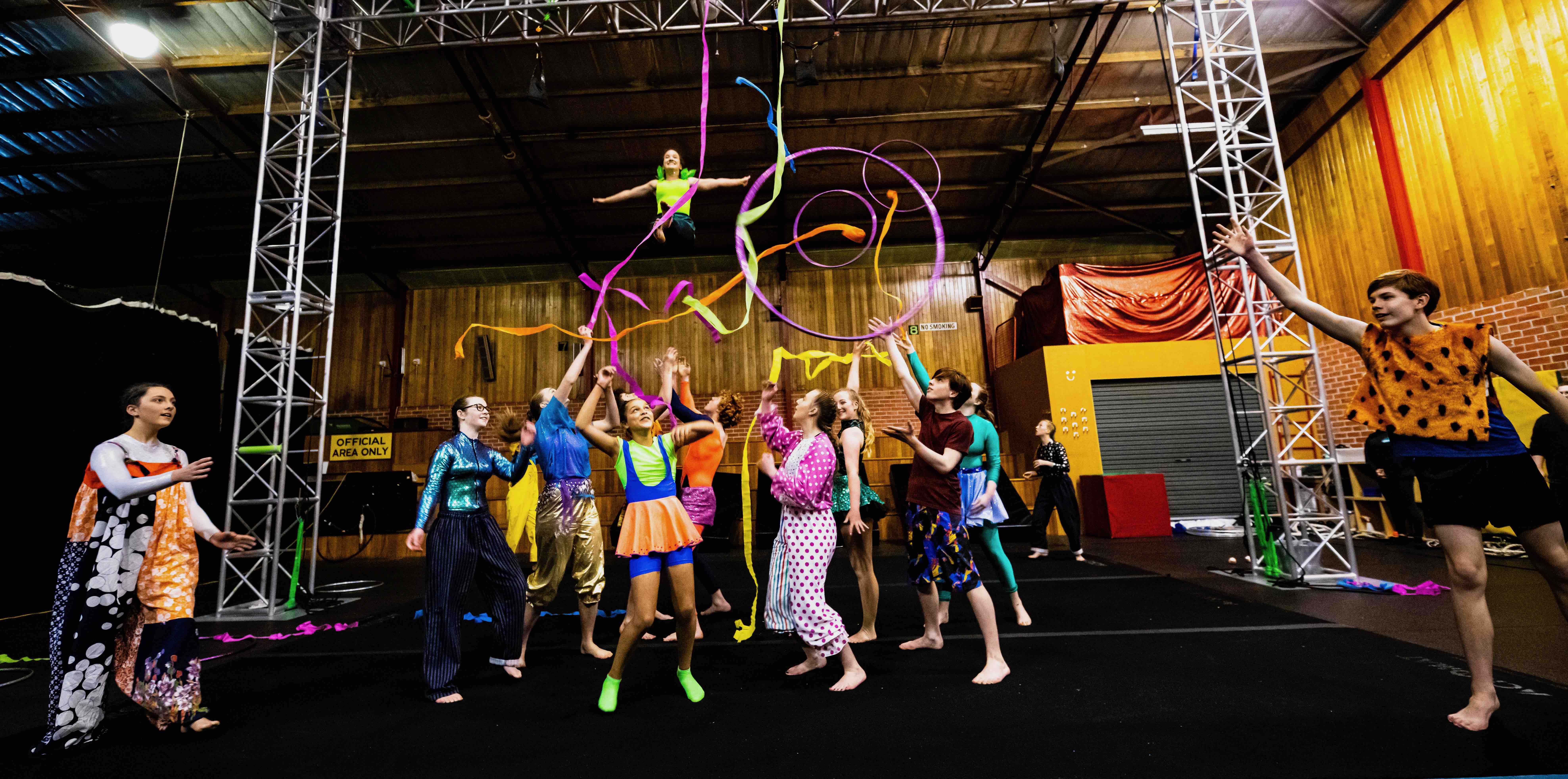 Spring into Action 2020, colourful group of young circus performers in a group tossing streamers in the air in celebration